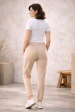 Γυναίκα με ανοιχτόχρωμη επιδερμίδα φοράει μπεζ παντελόνι φόρμας με λάστιχο στη μέση και ίσια γραμμή μέχρι τον αστράγαλο, βασισμένο στο πατρόν του προϊόντος.