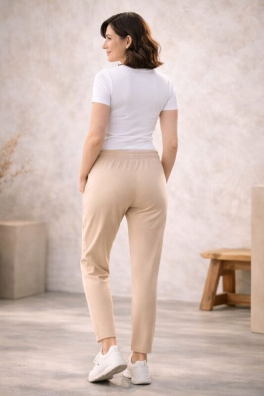 Γυναίκα με ανοιχτόχρωμη επιδερμίδα φοράει μπεζ παντελόνι φόρμας με λάστιχο στη μέση και ίσια γραμμή μέχρι τον αστράγαλο, βασισμένο στο πατρόν του προϊόντος.