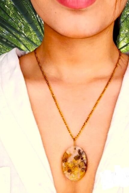 Χειροποίητο μενταγιόν οβάλ με αληθινά άνθη αμυγδαλιάς και φύλλα χρυσού μέσα σε υγρό γυαλί.