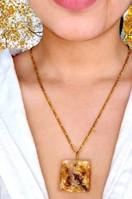 Χειροποίητο μενταγιόν τετράγωνο με αληθινά άνθη αμυγδαλιάς και φύλλα χρυσού σε υγρό γυαλί.