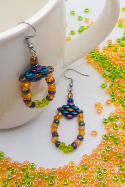 Ethnic, κρεμαστά σκουλαρίκια θηλιές (loops). Ξεκινούν από ένα μικρό ρόμβο από χάντρες Superduo σε χρυσό, πετρόλ και λαδί και καταλήγουν σε μία θηλιά από γυάλινες ιριδίζουσες seed beads χάντρες σε πορτοκαλί, ανοιχτό πράσινο και dark rainbow.