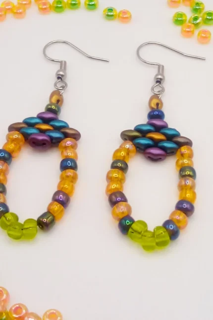 Ethnic, κρεμαστά σκουλαρίκια θηλιές (loops). Ξεκινούν από ένα μικρό ρόμβο από χάντρες Superduo σε χρυσό, πετρόλ και λαδί και καταλήγουν σε μία θηλιά από γυάλινες ιριδίζουσες seed beads χάντρες σε πορτοκαλί, ανοιχτό πράσινο και dark rainbow.