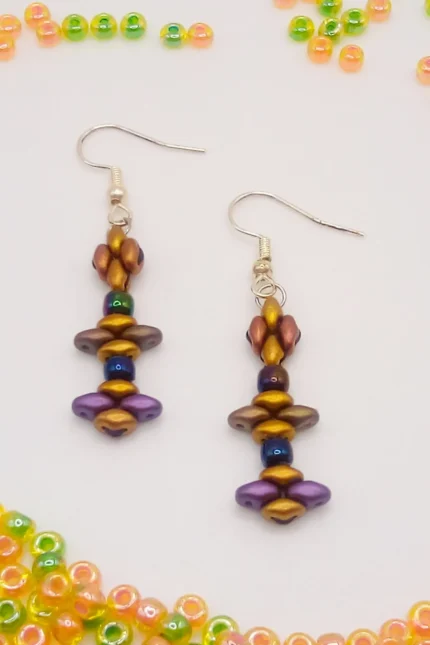 Tribal, κρεμαστά σκουλαρίκια μπάρες από Superduo χάντρες σε σατινέ υφή και σε ένα συνδυασμό γήινων τόνων του χρυσού, μπρονζέ, μωβ και καφέ. Κλείσιμο με γαντζάκι και στοπάκια σιλικόνης.