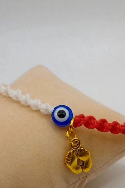 Γυναικείο μαρτάκι, αφιερωμένο στις μέλλουσες και νέες μανούλες ή/και στην μέλλουσα ή νέα γιαγιά. Πλεγμένο από δύο νήματα (λευκό/κόκκινο) του 1mm, σε πλέξη DNA, που καταλήγουν σε ένα ματόχαντρο στο κέντρο του βραχιολιού. Στο πλάι βρίσκουμε μία χάντρα με σταυρουδάκι για καλή τύχη, σε τρία χρώματα (ροζ/γαλάζιο/κόκκινο). Το σχέδιο ολοκληρώνεται με κρεμαστό στοιχείο παιδικά πατουσάκια (σε χρυσό χρώμα), δίπλα από την χάντρα ματάκι. Με αυξομειούμενο κλείσιμο ώστε να ταιριάζει σε κάθε καρπό.