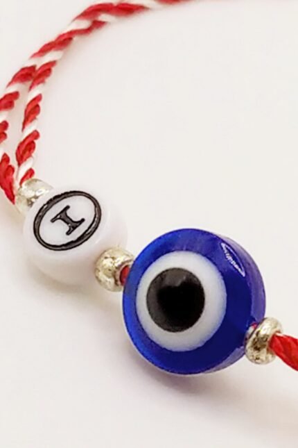 Προσωποποιημένο μαρτάκι με ματόχαντρο (10mm) και ακρυλική χάντρα με το αρχικό της επιλογής σας στα Ελληνικά. Πλαισιωμένο από ασημί ανοξείδωτα χαντράκια. Φτιαγμένο από διπλό μαρτιάτικο κορδόνι 1mm. Με αυξομειούμενο κλείσιμο ώστε να ταιριάζει σε κάθε καρπό. Σε τρία standard μεγέθη, παιδικό, ανδρικό και γυναικείο, αλλά μπορεί να γίνει και στο ακριβές μέγεθος που θέλετε.