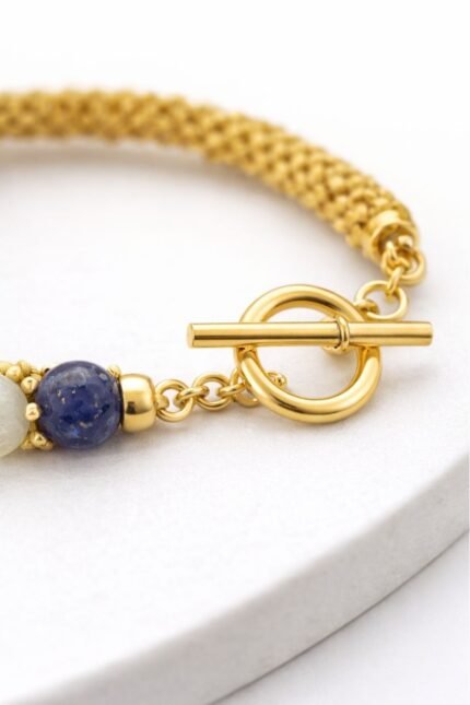 18K gold plated toggle clasp attached to a handmade bracelet with gemstone bead, close-up on white background.